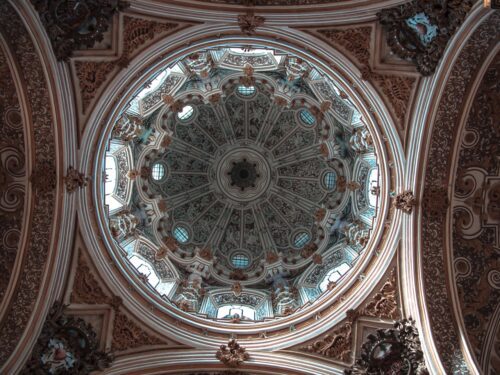 A stunning view of the intricate dome ceiling inside the Granada Cathedral.