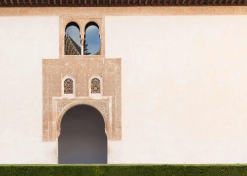 Detailed shot of an Arabic-style building's ornate arch and windows in a serene setting.