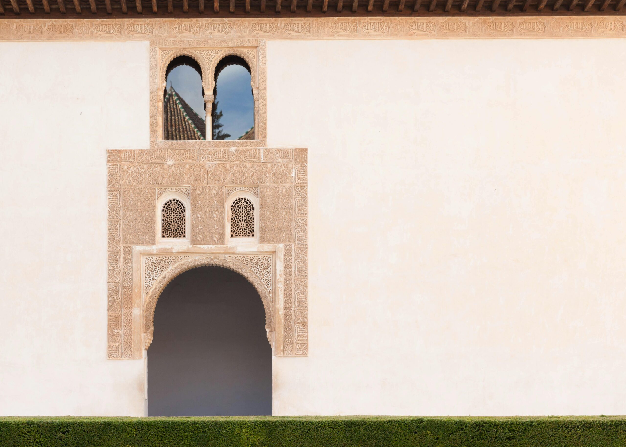 Detailed shot of an Arabic-style building's ornate arch and windows in a serene setting.